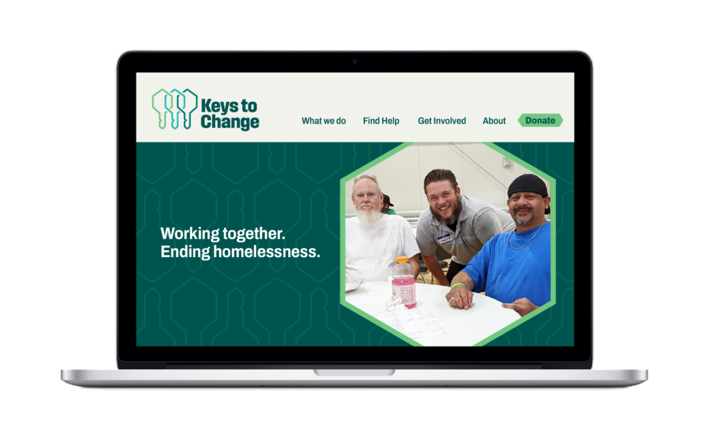 A laptop featuring a webpage with the logo for Keys to Change, a green background, a photo of three individuals smiling at a table, and the tagline “Working together. Ending homelessness.”