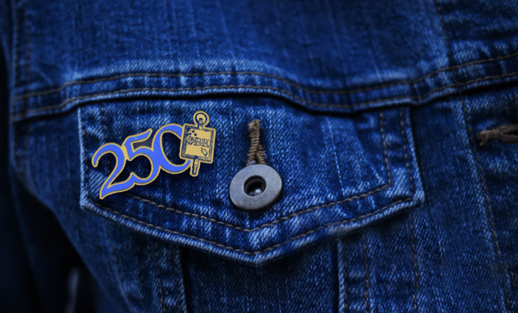 A mockup of an enamel pin of the 250 campaign logo on a jean jacket pocket.